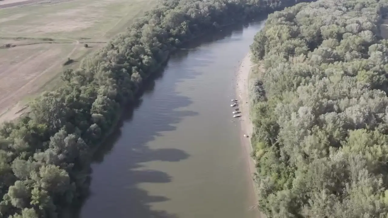 Drónfelvétel: a Tisza kanyarulata erdős partokkal, a homokpadnál kikötött hajókkal